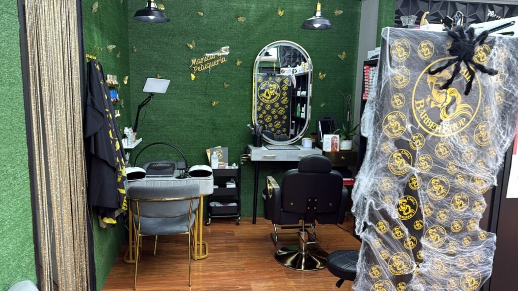 Zona de trabajo de barbería y peluquería con sillón, espejo y puesto de manicura