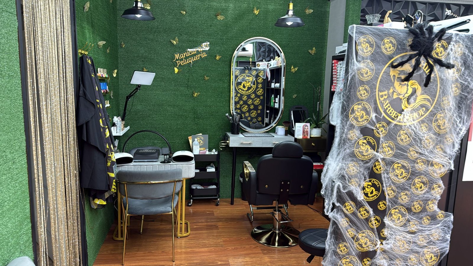 Zona de trabajo de barbería y peluquería con sillón, espejo y puesto de manicura